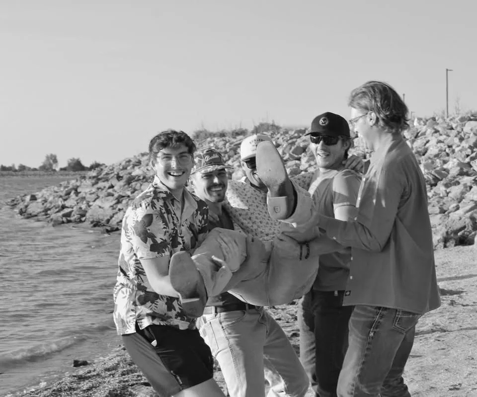 Friends laughing together during an outdoor celebration by the water.