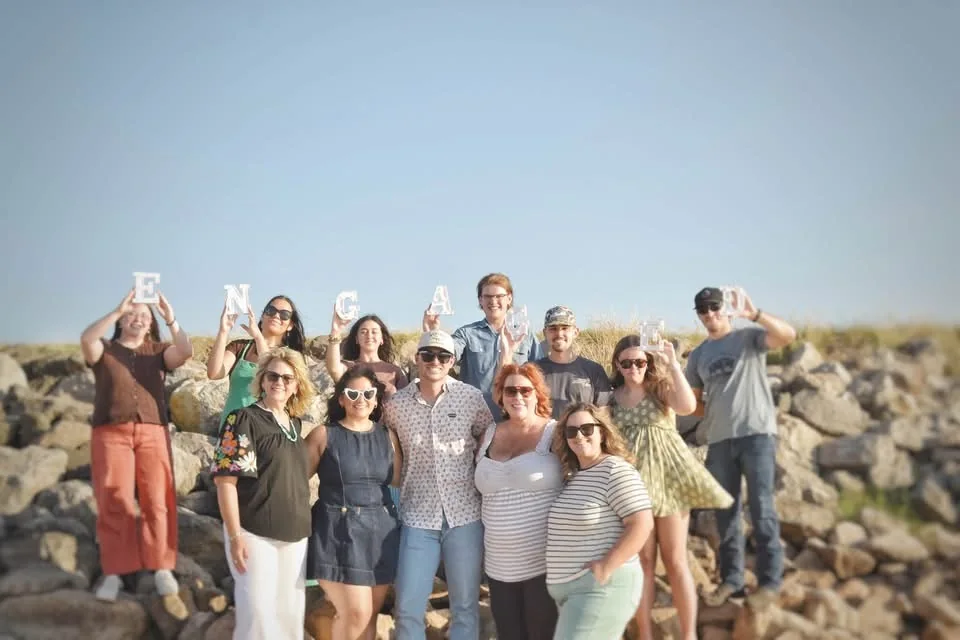 A large group of friends gathered for a portrait beside the water.